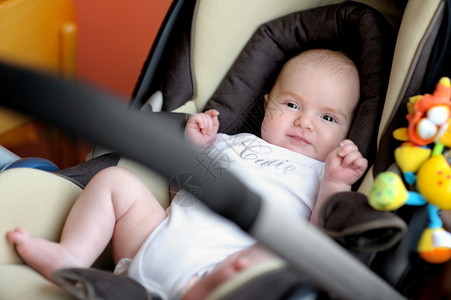 婴儿汽车座椅两个月大的婴儿坐在汽车座椅上腰带压痛女儿眼睛孩子女孩玩具童年幸福白色背景