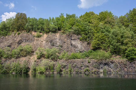 穿石坡湖山坡由湖边的拜萨尔特岩石制成绿色喷发树木火山岩蓝色树叶自然公园表面植物棕色背景