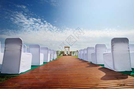 内地与一排椅子桌子刀具新娘婚姻餐具花园餐饮白色派对丝带背景