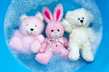 兔子气泡洗衣洗涤水分中带玩具熊的浸泡式兔子娃娃盆地泡沫经济黑发工作气泡篮子蓝色身体肥皂背景