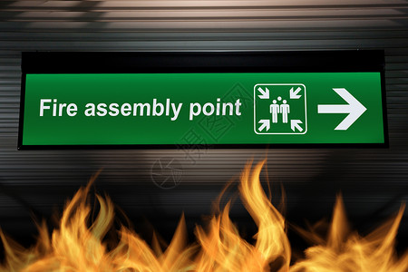 质量意识培训天花板上挂着绿色的火集合点标志 下面的地面上燃烧着火焰 基于安全的质量意识概念背景