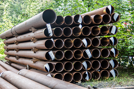 格林尔滕为煤气管道堆铺的长长生锈钢管技术绿色贮存棕色钢铁金属树木基础设施树叶煤气管背景