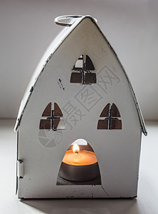带烛光的圣诞屋小屋陶瓷火焰红色茶色金属蜡烛手表腐烂白色背景图片