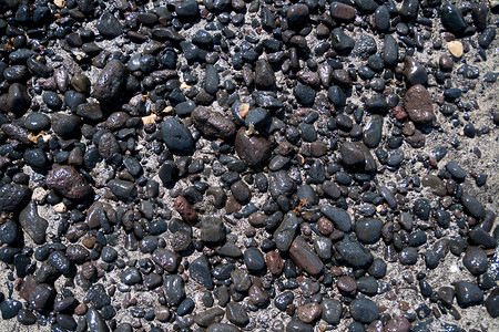 海滩上的火山黑石头背景图片