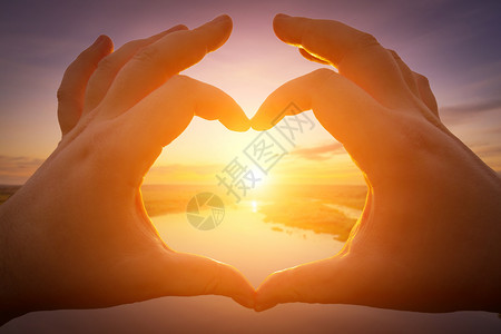 太阳形状双手在心的形状中 面对日落太阳橙子晴天阳光背景