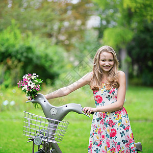 骑自行车的美丽女孩农村假期公园白色闲暇女孩活动绿色裙子花朵背景图片
