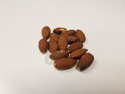 白桌或白桌上的褐杏仁营养白色桌子盐渍小吃坚果棕色食物背景图片