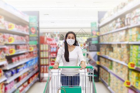 亚裔女性在超市上戴面罩 在超市下铺推货车杂货店购物暴发流感消费者杂货商店市场店铺大车背景图片