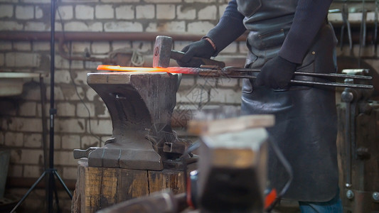 肌肉人的铁匠 用铁锤铸造钢刀制造业金工男人金属劳动男性工业艺术虎钳工作背景图片