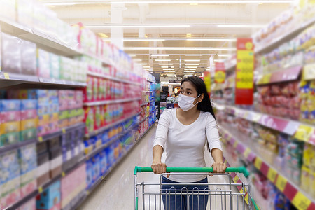亚裔女性在超市戴面罩推车隔离店铺女士社交顾客市场购物消费者百货口罩背景图片