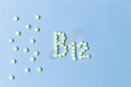 氰黄色药丸在蓝色背景上形成 B12 字母表的形状 复合维生素 营养 健康的生活方式 食品添加剂 复制空间 软焦点 模糊的背景红肉矿背景