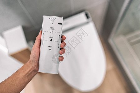 带遥控器的智能日式坐浴盆自动坐便器 无需使用卫生纸即可轻松用水冲洗 在家浴室现代生活方式背景图片