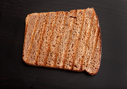 木制桌上的烤黑麦面包食物生产桌子炙烤鸟瞰图早餐油炸面包条纹黑色背景图片