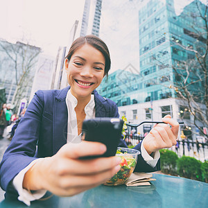 布莱恩特午餐休息时使用智能手机的年轻商业女青年女士城市成人短信商界微笑混血女性女孩公园背景