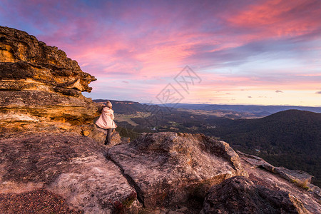 看着澳洲山丘的暴烈日落闲暇黄色悬崖山脉女性旅行砂岩旅游岩石成人背景