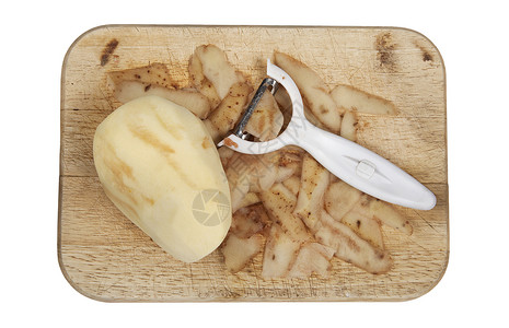 马铃薯削皮器Raw马铃薯在木制切削板上剥皮 砍断了皮革背景