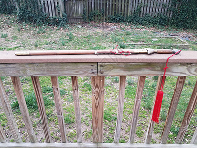 中国剑在铁栏上挂着红帆船红色栏杆武术木头栅栏甲板草地护套背景图片