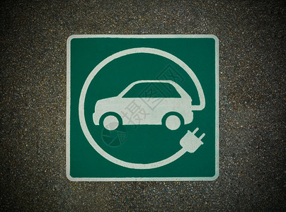 插头标志EV  电动车辆充电站标志 沥青纹理上的E标志电气燃料电力运输汽油力量电动车活力绿色街道背景