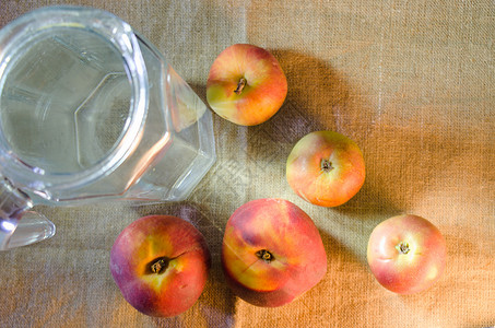 粗布背景上的苹果 桃子和一壶水背景图片