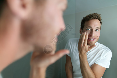 防湿疹面霜面霜年轻人把护肤美容产品放在脸上保湿皮肤 男性美容面部护理在家中的生活方式 冬季为干性皮肤应用润肤霜的人背景
