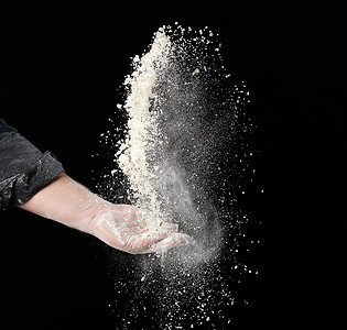 面包师的手把一些白面粉扔在黑面包上男性男人小麦灰尘飞溅餐厅烹饪食物食谱厨房背景