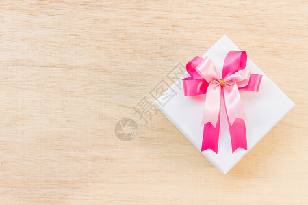 粉色丝带弓和木背景的白色礼品盒木头框架礼物木板丝带棕色问候语背景图片