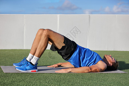 夏季瑜伽减肥健身男子做体重臀部地板桥式瑜伽练习 适合运动员在草地上的夏季户外健身指导课上锻炼臀部肌肉和臀部背景