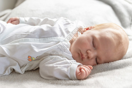 产褥期美丽的新生男孩睡在毯子上背景