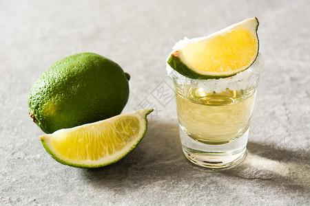 龙舌兰酒素材墨西哥的金龙舌兰加灰色背景的石灰和盐液体水果桌子酒精饮料金子玻璃背景