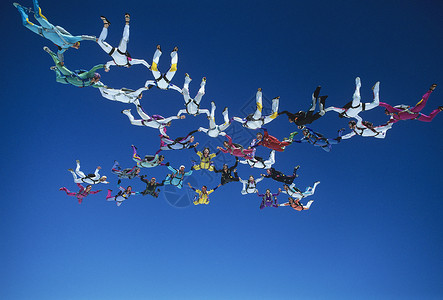 向下降落男士Skydivers 握手在蓝天的网状编织中双腿降落伞极限危险乐趣跳伞跳伞员男人风险成人背景