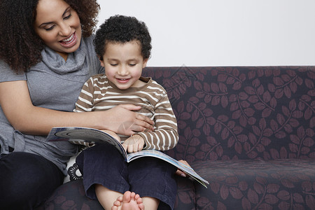 三季度母亲与儿子一起在沙发上阅读书56成人家长男生女性阅读男性孩子专注闲暇场景背景