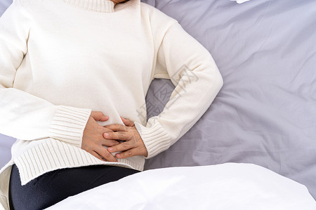 双十12年轻妇女躺在床上胃痛 在医疗或日常生活概念上受到保健护理的治疗 第12条药品腹痛便秘女性痛苦腹泻经期成人长椅伤害背景
