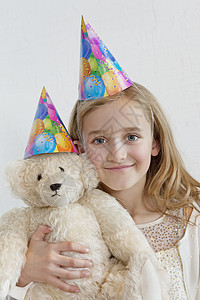 党生日的素材一个戴着党帽 带着柔软玩具的快乐年轻女孩的肖像 彩色背景背景