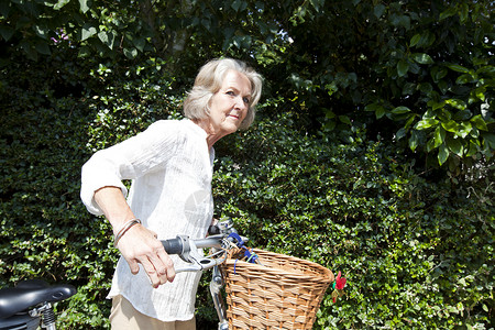 在后院骑自行车的活跃老年妇女闲暇男性技术男人婚姻生活成人幸福骑术女士长椅背景图片