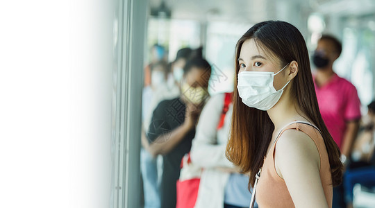 公车站身戴外科面具和等候的年轻亚洲女乘客背景