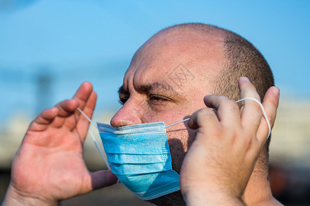 带医疗防护面罩的年轻人展示了大流行病手术公共场所街道环境隔离流感面具城市男性药品背景图片