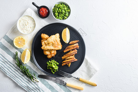 英国食品鱼和薯条配啤酒糊鳕鱼和薯条 一边是塔塔酱和糊状豌豆 放在质朴的白色石头桌面上 文字一侧的视图空间背景