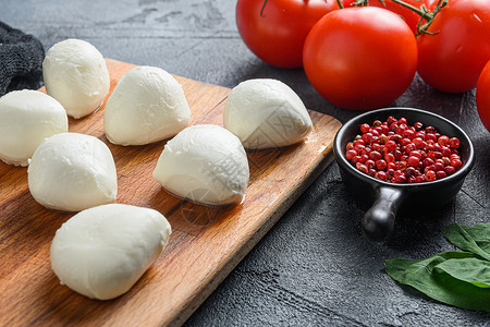 莫扎里拉奶酪奶酪球配新鲜罗勒叶和樱桃番茄 意大利卡普雷塞沙拉的配料 在黑色布料和灰色混凝土背景上特写背景