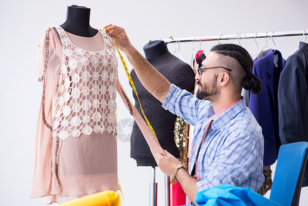 裁缝粉笔在新设计讲习班上工作的男裁缝手工业作坊设计师男性材料磁带衣服人体裙子服装背景