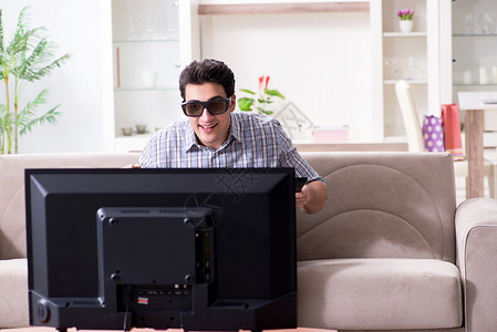 男人在家看3D电视沙发监视器长椅屏幕控制渠道房间展示技术微笑背景图片