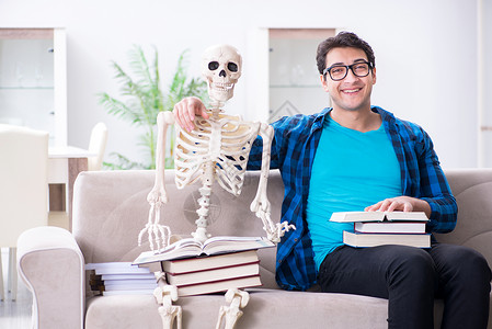 学生在学习时有骨架准备考试图书拥抱青少年风暴颅骨家庭作业男人阅读大学教育背景图片