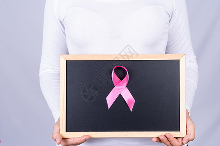 由妇女持有的黑板上的乳腺癌认识丝带 医疗 广告概念保健等信息学知识癌症帮助幸存者外科诊断活动女孩治愈化疗生存背景图片