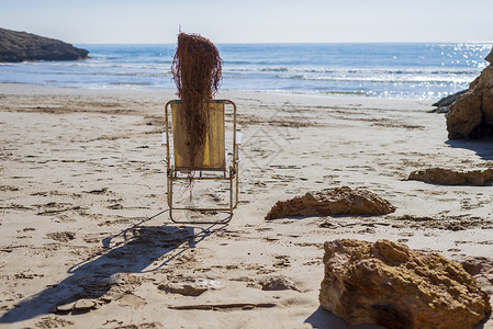 海滩椅上Trunk娃娃的侧边景色模拟人晒太阳背景图片