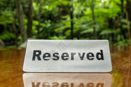 保留标志在一家餐厅的层压木桌上用不锈钢板制成 背景是树木和森林木头服务用餐盘子派对客人食物庆典层压座位背景图片