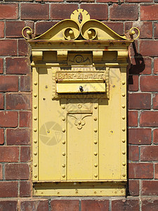 旧黄色邮箱金属熟料石方邮递员狭缝铆钉古董历史性信箱盒子背景图片