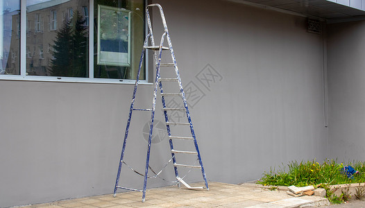 一个施工梯子站在灰色建筑的外墙旁边 门外 一步梯式平台 (笑声)背景图片