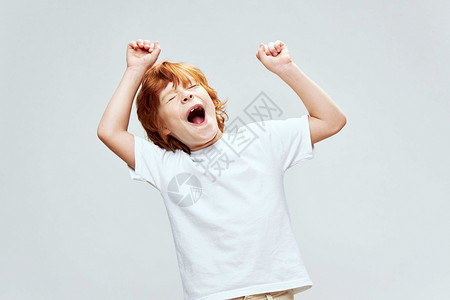 红发男孩张开嘴 双手握在头顶的情绪上;白色T恤花风景背景图片