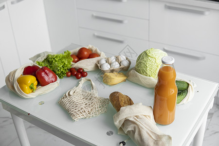 厨房装水果环保帆布购物袋 蔬菜 水果装在可重复使用的生态棉袋里 橙汁装在桌上的玻璃瓶里 零浪费购物理念 多次使用 再利用 回收购物者塑料环背景