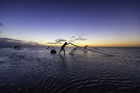 黑影渔民在清晨蓝色反射日落文化太阳海洋天空橙子海滩旅行背景图片