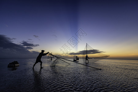 黑影渔民在清晨文化蓝色太阳天空反射旅行钓鱼日落海洋渔夫背景图片